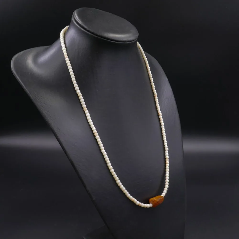 Halskæde af hvide koralperler (Angel-skin) prydet med rav-stykke